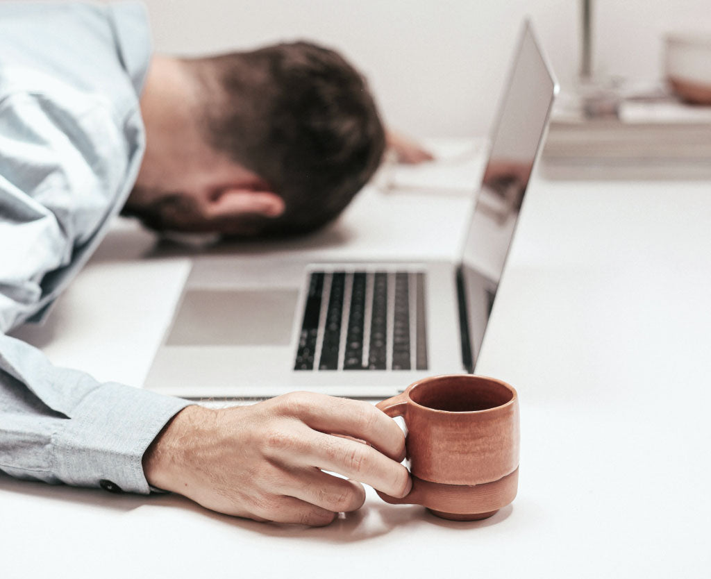 Man Asleep On Laptop Holding Coffee